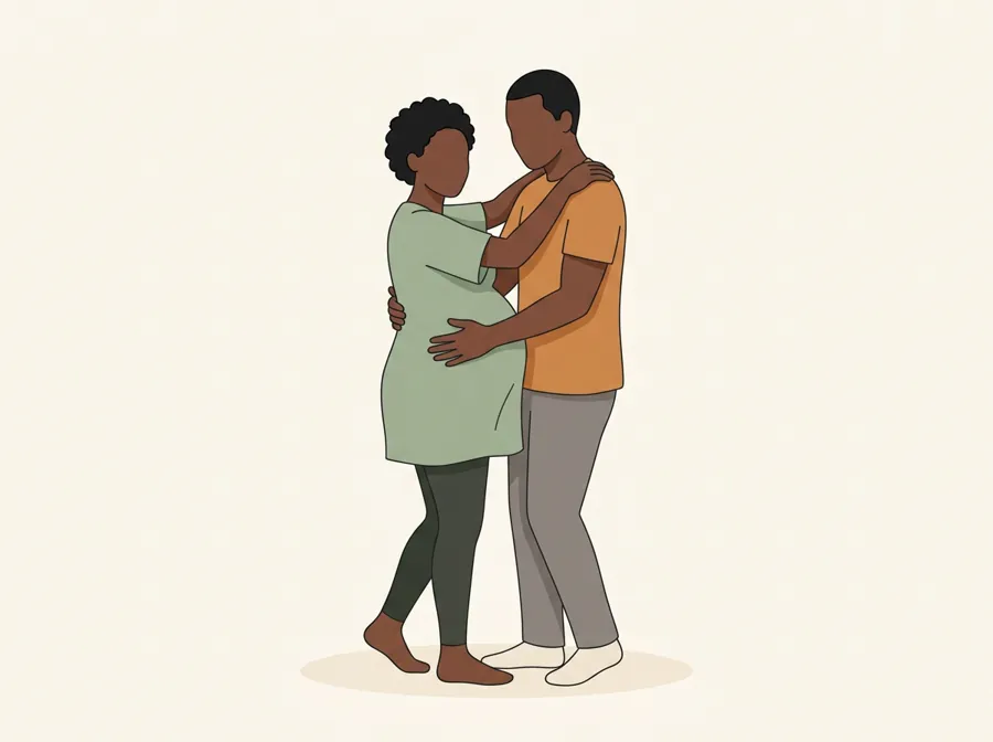 A pregnant woman and her partner standing close, swaying together, his hands at her lower back.